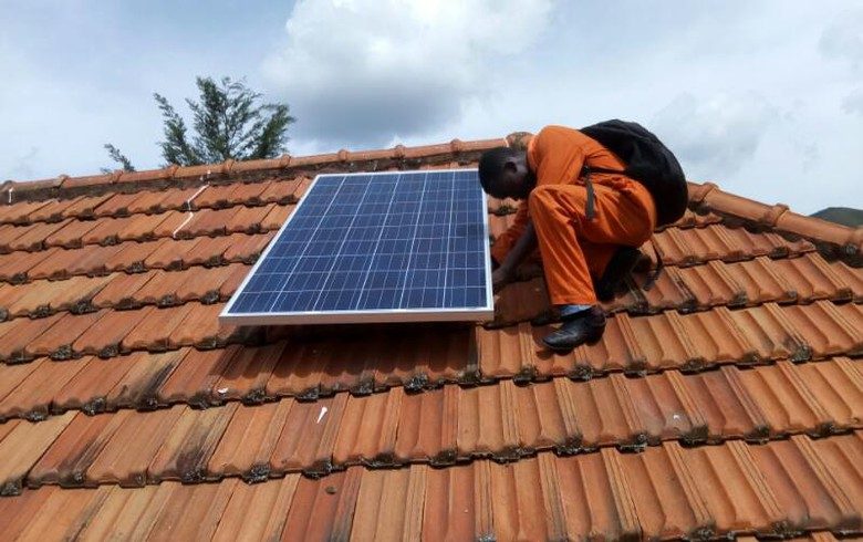 Technician fixing a solar panel onto a tiled roof