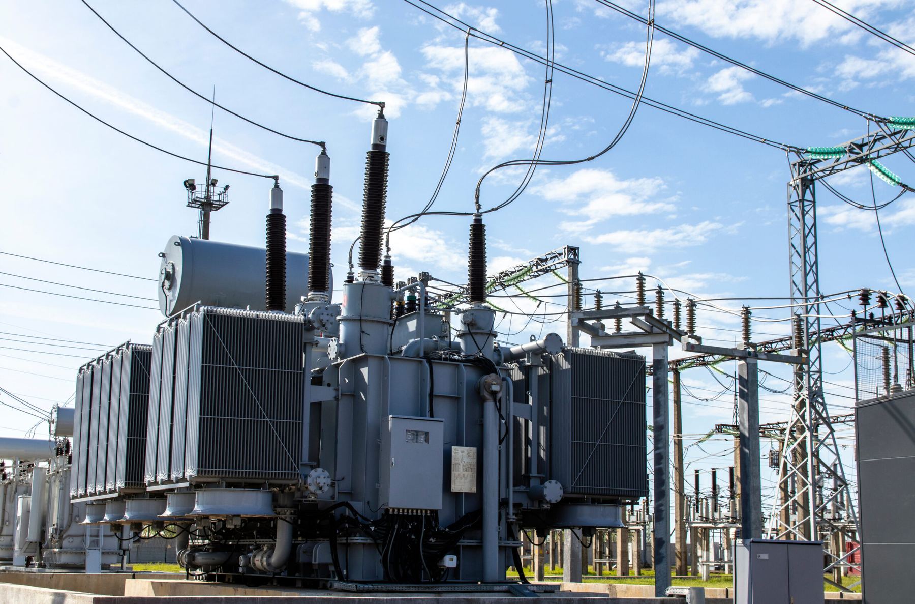 High-voltage transformers at an electrical substation under a blue sky