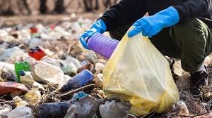 Gloved hands collecting plastic bottles for recycling